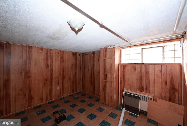 basement with wood walls, radiator, and carpet