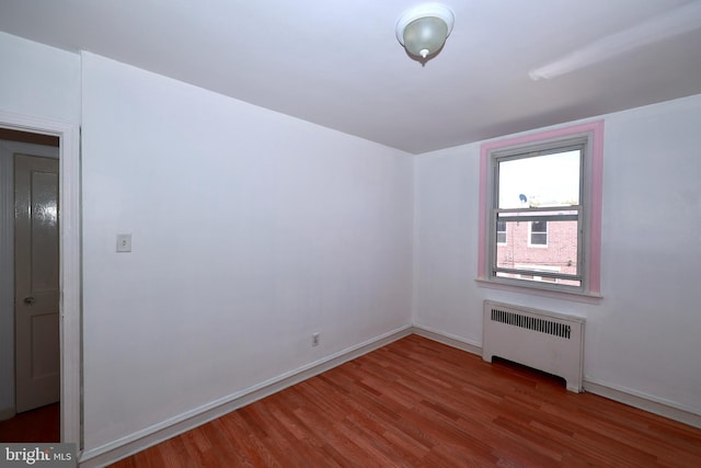 spare room with radiator heating unit and hardwood / wood-style flooring