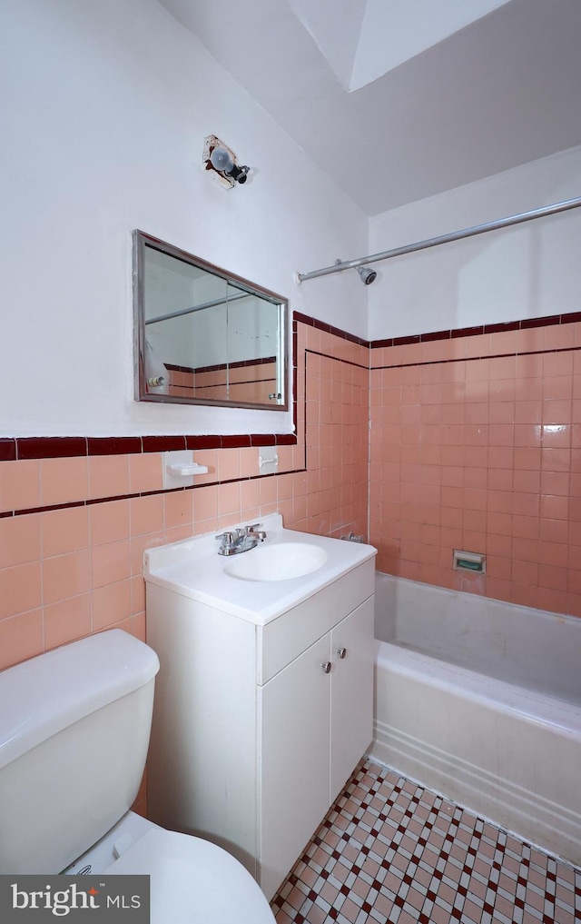 full bathroom with vanity, toilet, tile walls, and tiled shower / bath