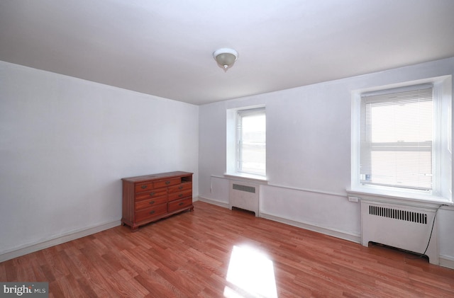 interior space with light hardwood / wood-style flooring, multiple windows, and radiator