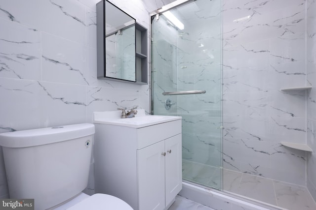 bathroom with vanity, toilet, tile walls, and a shower with shower door