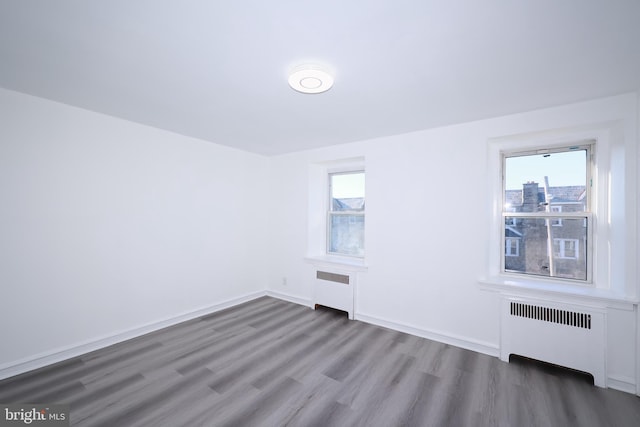 spare room with radiator heating unit and dark hardwood / wood-style floors