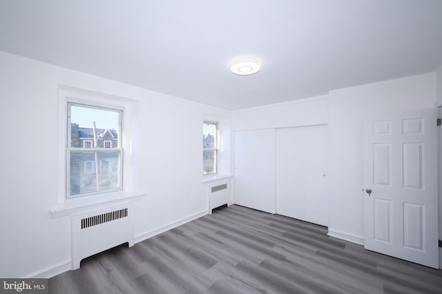 interior space featuring radiator, a closet, dark wood-type flooring, and multiple windows