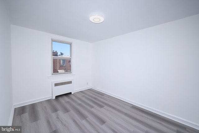 empty room with light hardwood / wood-style floors and radiator heating unit