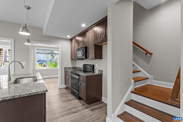 kitchen featuring a wealth of natural light, sink, black appliances, and light stone countertops