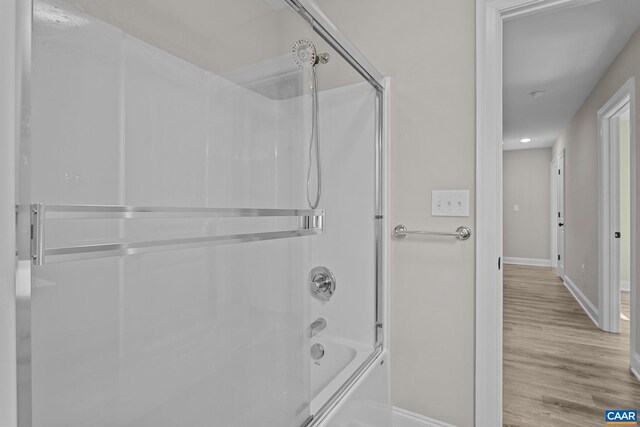 bathroom with hardwood / wood-style floors and bath / shower combo with glass door