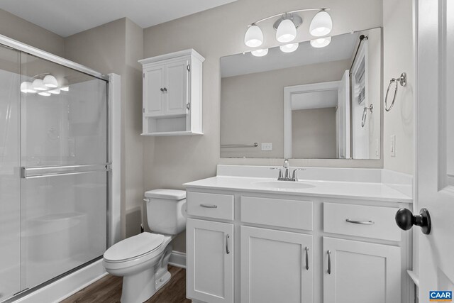 bathroom with toilet, walk in shower, vanity, and hardwood / wood-style flooring