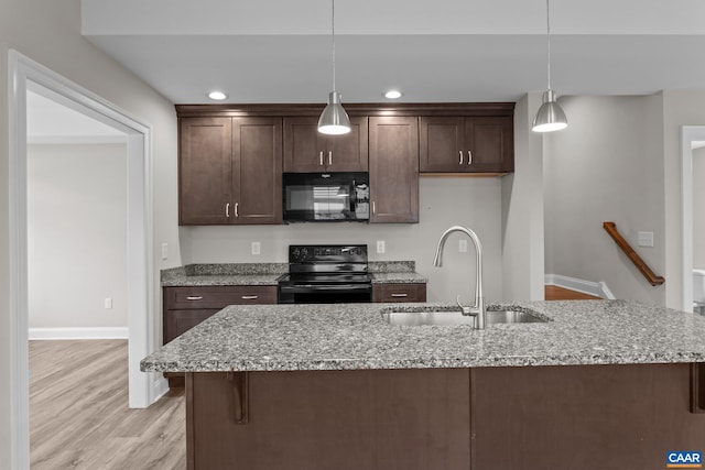 kitchen featuring light hardwood / wood-style flooring, sink, black appliances, pendant lighting, and light stone counters