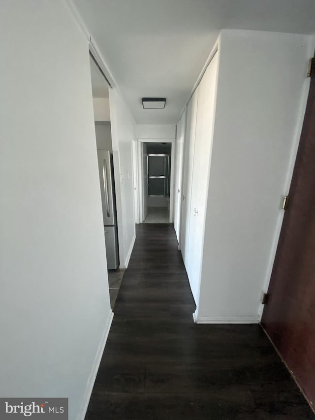 hallway with dark wood-type flooring and baseboards