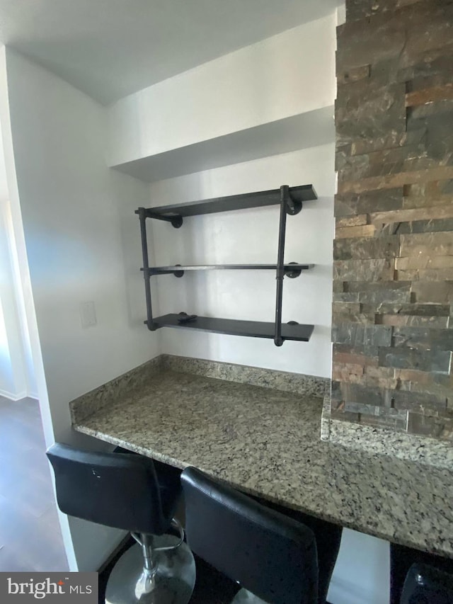 bar featuring stone counters and built in desk