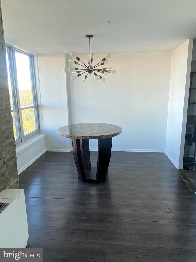 unfurnished dining area featuring dark wood finished floors, a chandelier, and baseboards