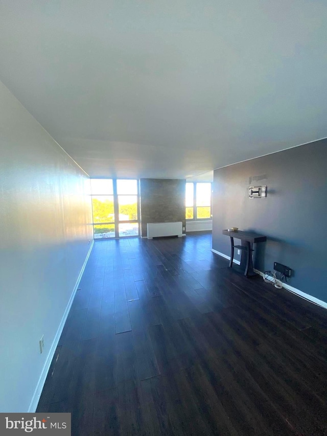 unfurnished living room featuring dark wood-style floors and baseboards