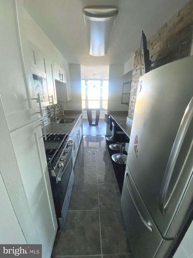 kitchen with stainless steel appliances, sink, dark tile patterned floors, and white cabinets