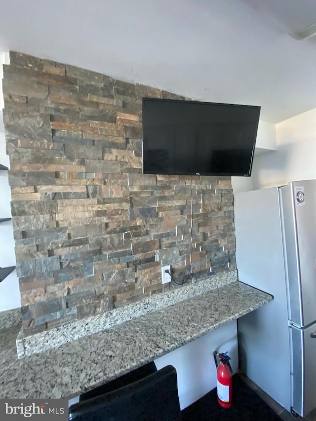 interior details featuring backsplash, stone countertops, and freestanding refrigerator