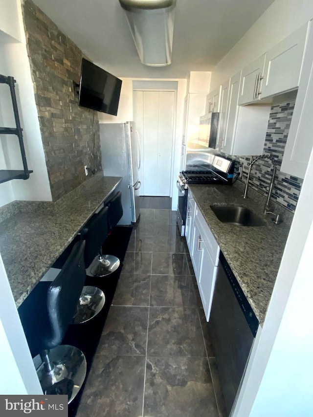 kitchen with decorative backsplash, freestanding refrigerator, white cabinets, dishwasher, and stainless steel gas range