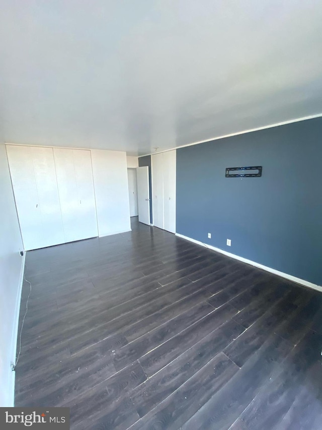 spare room with dark wood finished floors and baseboards