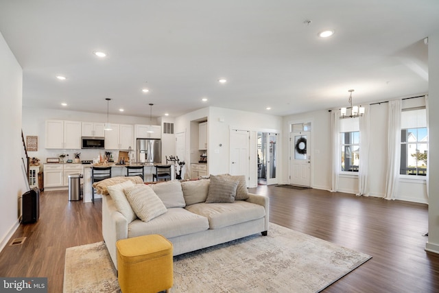 living room featuring dark wood-type flooring and a notable chandelier