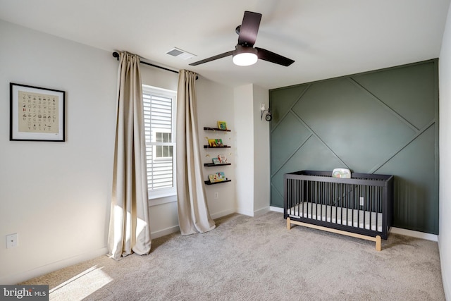 bedroom with ceiling fan, light carpet, and a crib