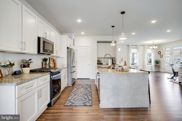 kitchen featuring dark hardwood / wood-style floors, appliances with stainless steel finishes, decorative light fixtures, and white cabinets