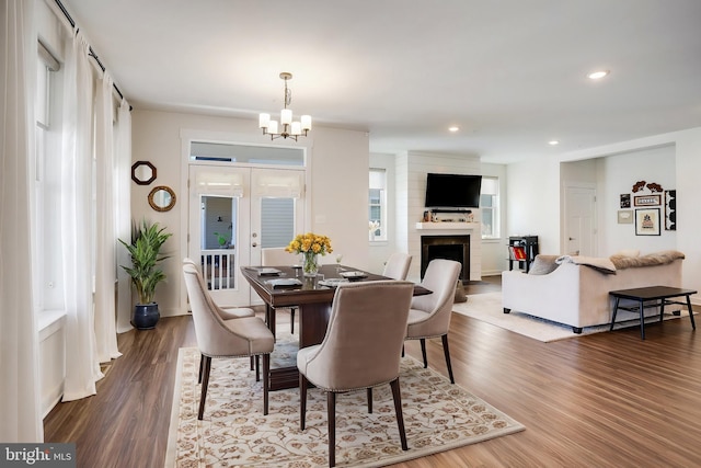 dining room with a notable chandelier, hardwood / wood-style flooring, and a large fireplace