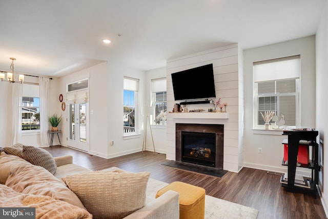 living room with a notable chandelier, a fireplace, and dark hardwood / wood-style floors