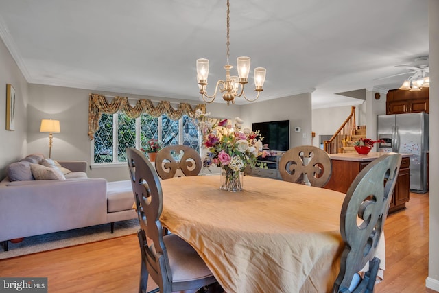 dining room featuring light hardwood / wood-style floors, ornamental molding, and ceiling fan with notable chandelier