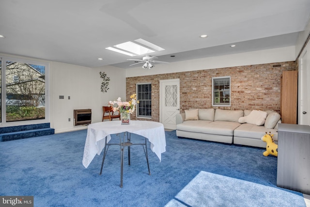 unfurnished living room featuring dark carpet, ceiling fan, heating unit, and a skylight