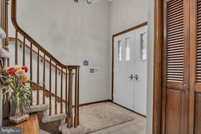 tiled entryway featuring a notable chandelier