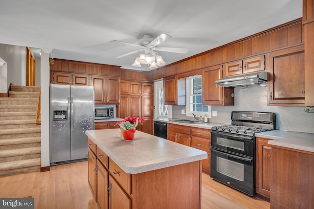 kitchen with sink, black appliances, light wood-type flooring, and a kitchen island