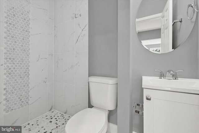 bathroom featuring toilet, vanity, and a tile shower