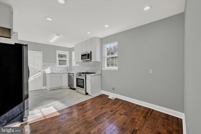 kitchen featuring tasteful backsplash, appliances with stainless steel finishes, light wood-type flooring, and white cabinets