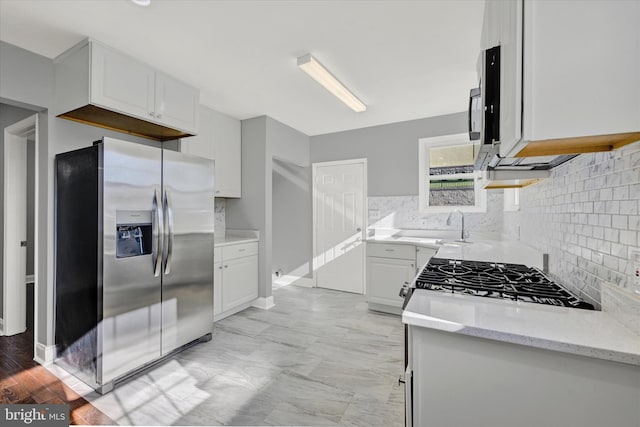 kitchen featuring tasteful backsplash, light stone countertops, gas range oven, stainless steel fridge, and white cabinets