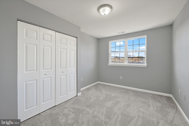 unfurnished bedroom featuring light carpet and a closet