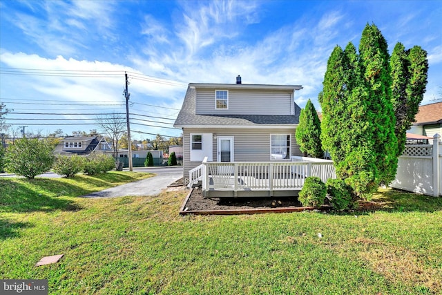 back of property featuring a deck and a lawn