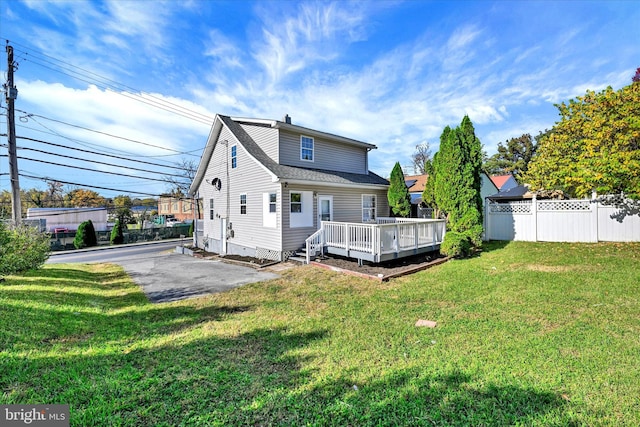 back of property with a yard and a wooden deck