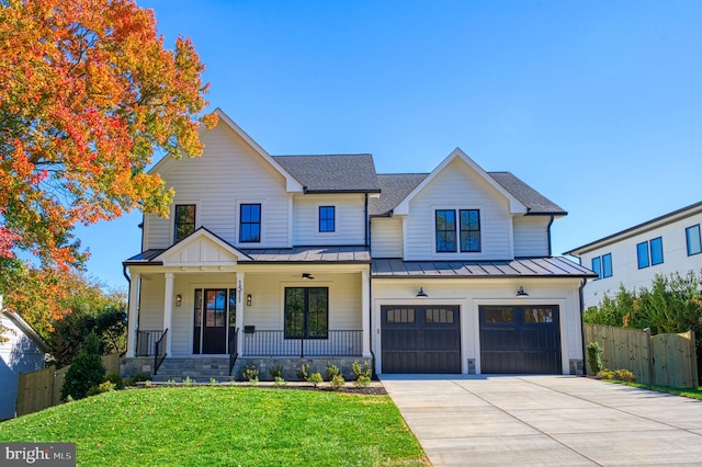 modern farmhouse with covered porch, a garage, and a front yard