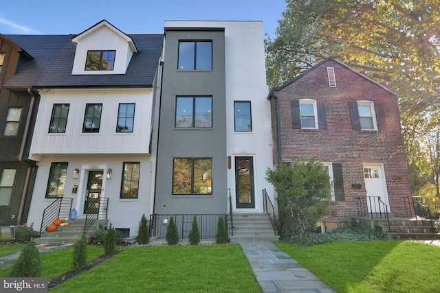 townhome / multi-family property with board and batten siding and a front yard