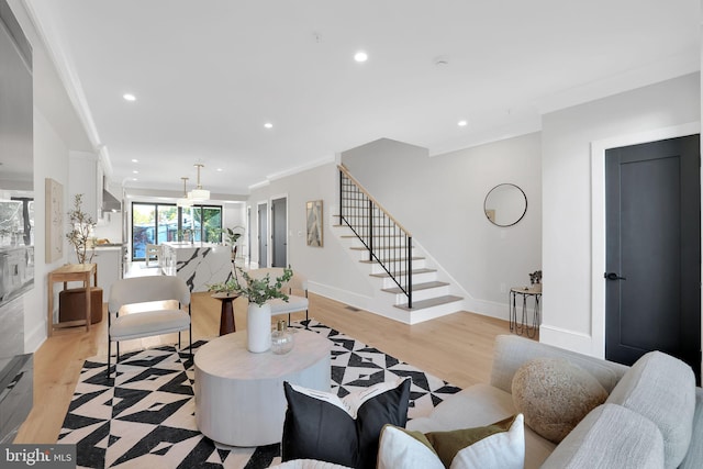 living room featuring stairs, baseboards, light wood-style floors, ornamental molding, and recessed lighting