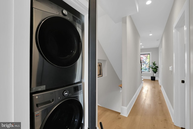 laundry room with light wood-type flooring, recessed lighting, baseboards, and stacked washer / drying machine