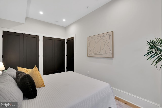 bedroom with baseboards, recessed lighting, two closets, and wood finished floors