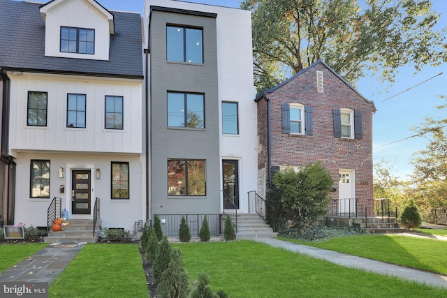 view of front of house featuring board and batten siding, brick siding, a front yard, and entry steps