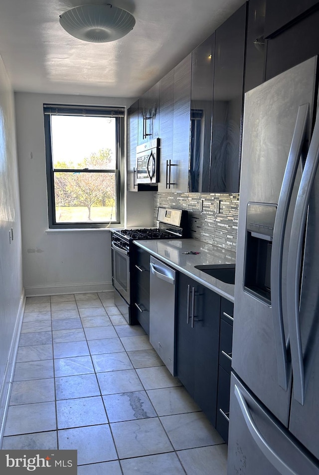 kitchen featuring light tile patterned floors, backsplash, stainless steel appliances, and sink