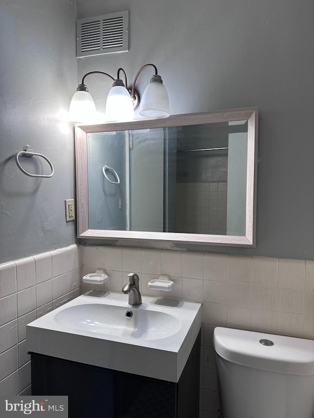 bathroom featuring vanity, tile walls, and toilet