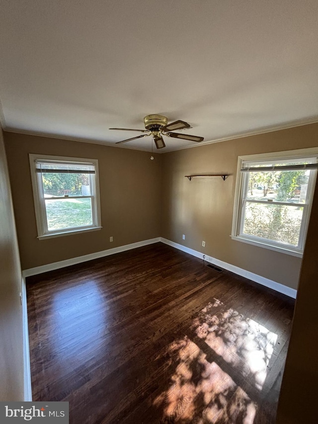 unfurnished room with ceiling fan, a healthy amount of sunlight, dark hardwood / wood-style flooring, and crown molding