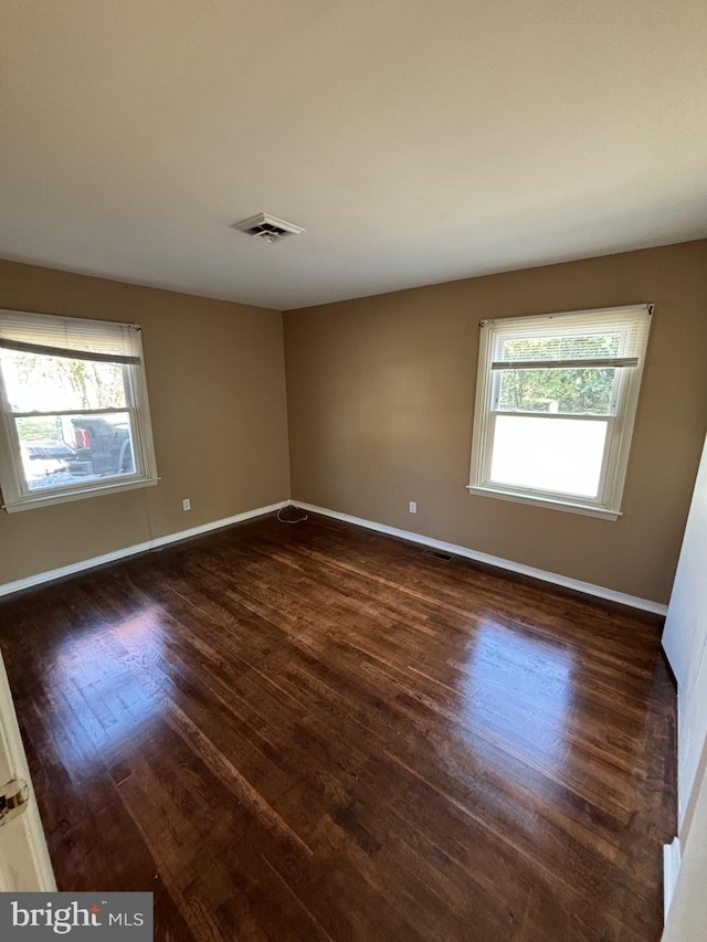 spare room with dark hardwood / wood-style floors and a wealth of natural light