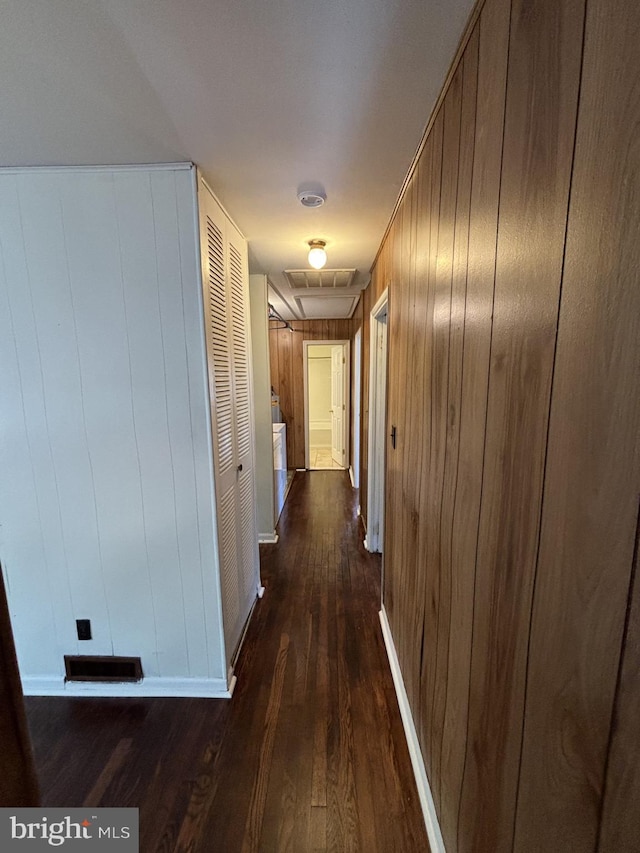 hall with dark wood-type flooring and wood walls