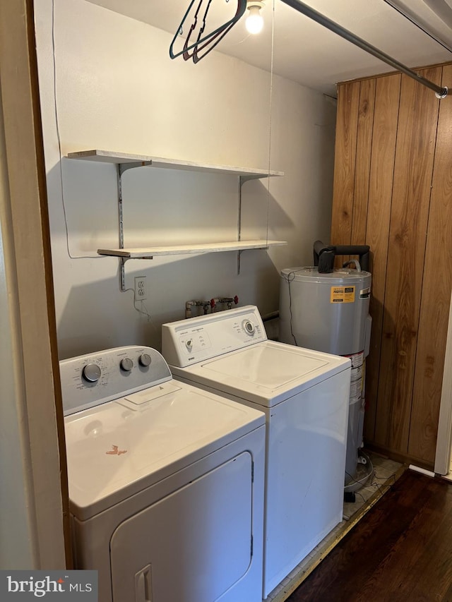 washroom featuring water heater, wooden walls, dark hardwood / wood-style floors, and washer and dryer