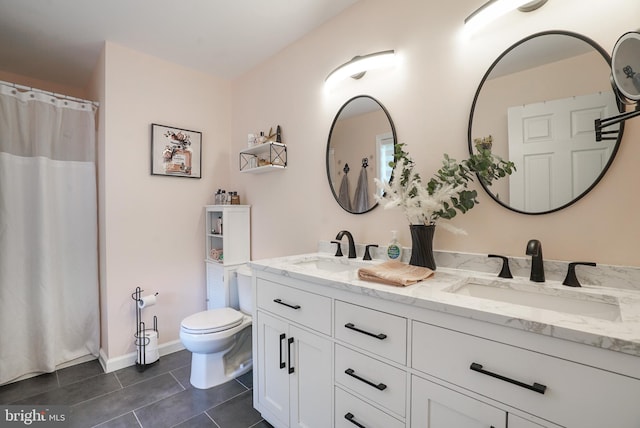 bathroom with toilet, vanity, and tile patterned floors