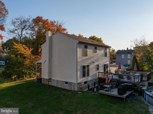 back house at dusk featuring a yard and a wooden deck