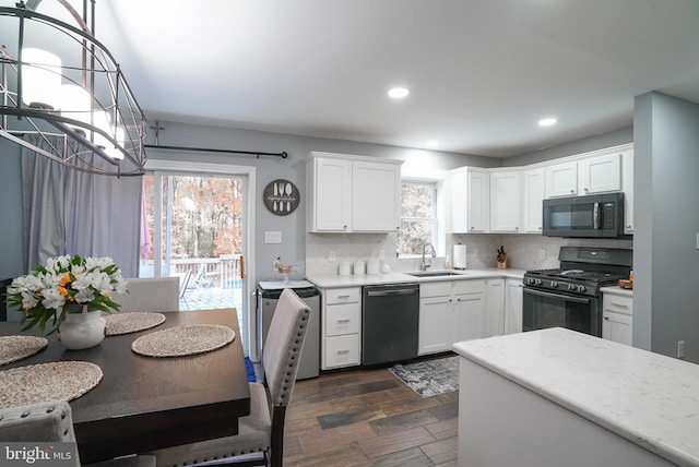 kitchen featuring dark wood-type flooring, sink, black appliances, white cabinets, and tasteful backsplash